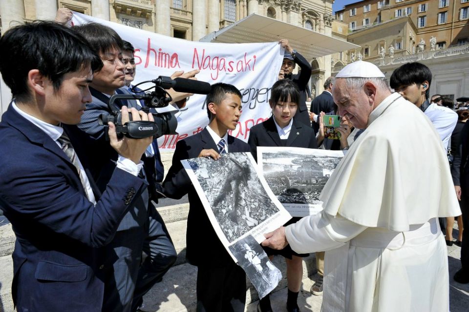 Pope Francis examines photos of the aftermath of the 1945 atomic bombing of Japan as he greets members of the Hiroshima and Nagasaki Youth Peace Messengers at his weekly general audience June 19. (CNS/Vatican Media) Pope Francis examines photos of the aftermath of the 1945 atomic bombing of Japan as he greets members of the Hiroshima and Nagasaki Youth Peace Messengers at his weekly general audience June 19. (CNS/Vatican Media)