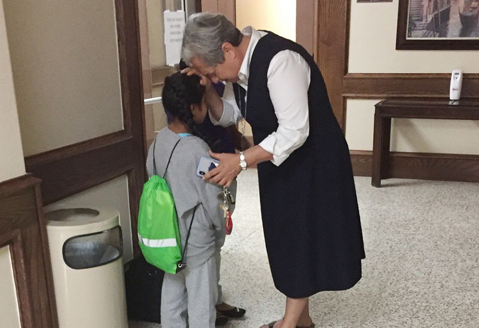 In this 2018 file photo, Sr. Norma Pimentel prays with a girl at Our Lady of San Juan National Shrine Basilica Hotel in McAllen, Texas. The child had been separated from her family. (CNS/GSR/Catholic Charities of the Rio Grande Valley)