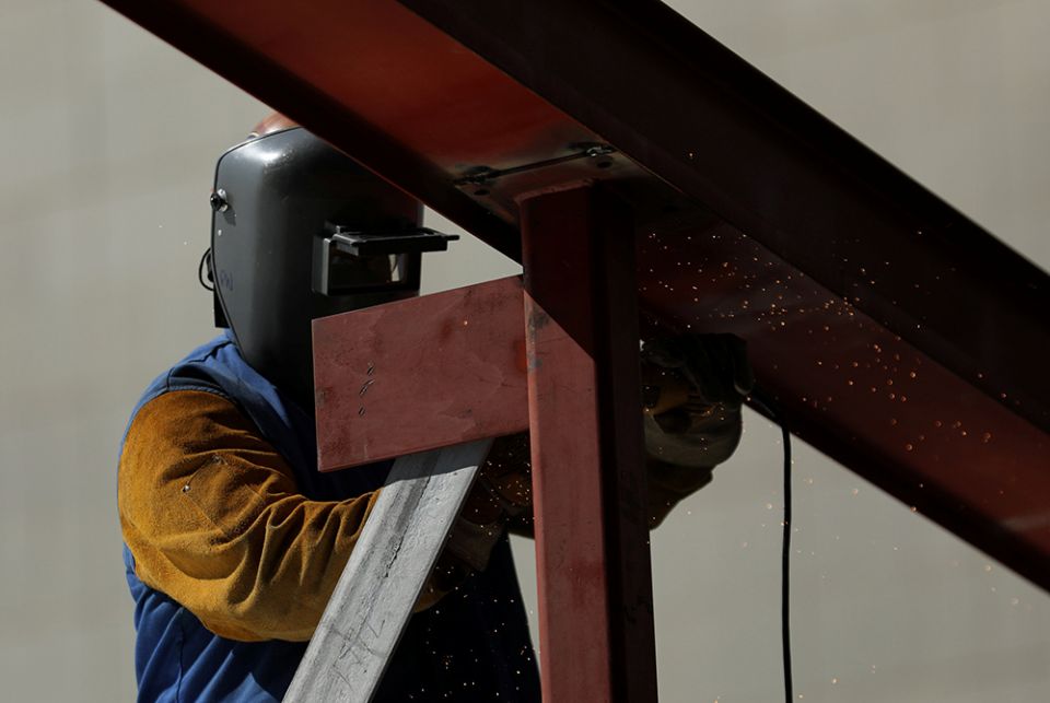 A construction worker uses a grinder on a metal beam A construction worker uses a grinder on a metal beam at a construction site Aug. 10, 2017, in Los Angeles. (CNS/Reuters/Mike Blake)