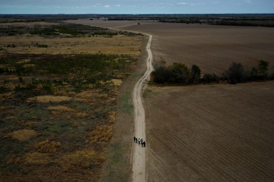 A group of migrants walk past plowed farmland near Penitas, Texas, Jan. 10, 2019. (CNS/Reuters/Adrees Latif)