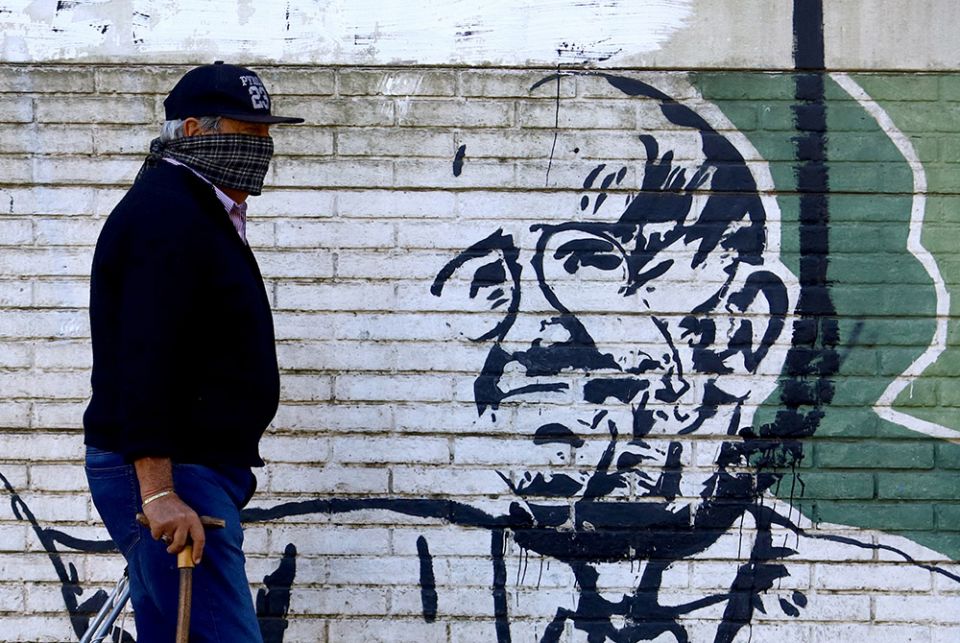 A man wearing a scarf as a protective measure against COVID-19 walks past a mural depicting Pope Francis on Easter, April 12, 2020, in Buenos Aires, Argentina. (CNS/Reuters/Matias Baglietto)
