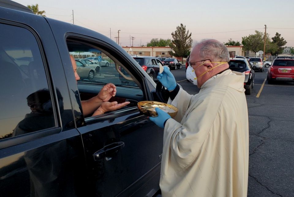 Bishop Peter Baldacchino wears a mask and gloves while giving Communion to a passenger of a vehicle during the Easter Vigil in the parking lot of the Cathedral of the Immaculate Heart of Mary in Las Cruces, New Mexico, April 11. (CNS) Bishop Peter Baldacchino wears a mask and gloves while giving Communion to a passenger of a vehicle during the Easter Vigil in the parking lot of the Cathedral of the Immaculate Heart of Mary in Las Cruces, New Mexico, April 11. (CNS)