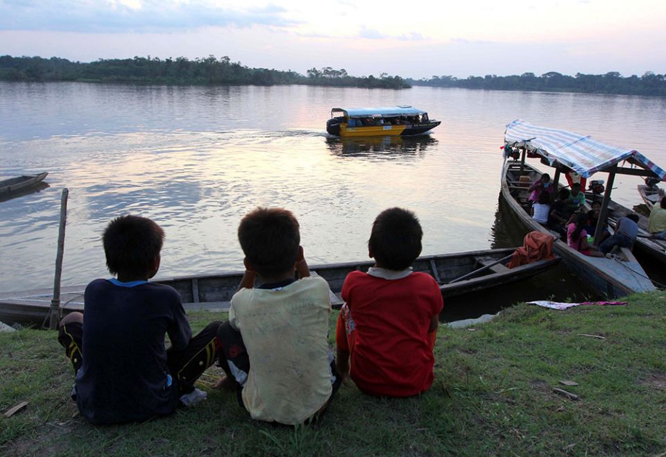 Kukama boys watch boats on the Amazon's Maranon River near Dos de Mayo in Peru's Loreto region. (CNS/Barbara Fraser)
