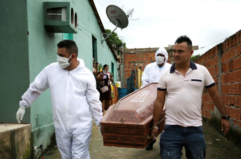 The relative of a person who died of COVID-19 and funeral workers wearing protective clothing and masks carry the victim's coffin in Manaus, Brazil, May 7. (CNS/Reuters/Bruno Kelly)
