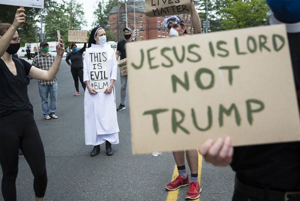 A woman religious and protesters in Washington gather near the Capuchin College June 2 as President Donald Trump and first lady Melania Trump visited the nearby St. John Paul II National Shrine. (CNS/Tyler Orsburn)