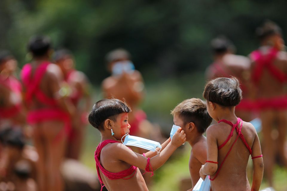 Young Yanomami try on protective masks as members of a medical team with the Brazilian army examine members of the tribe in the state of Roraima July 1, 2020, during the COVID-19 pandemic. (CNS/Reuters/Adriano Machado)
