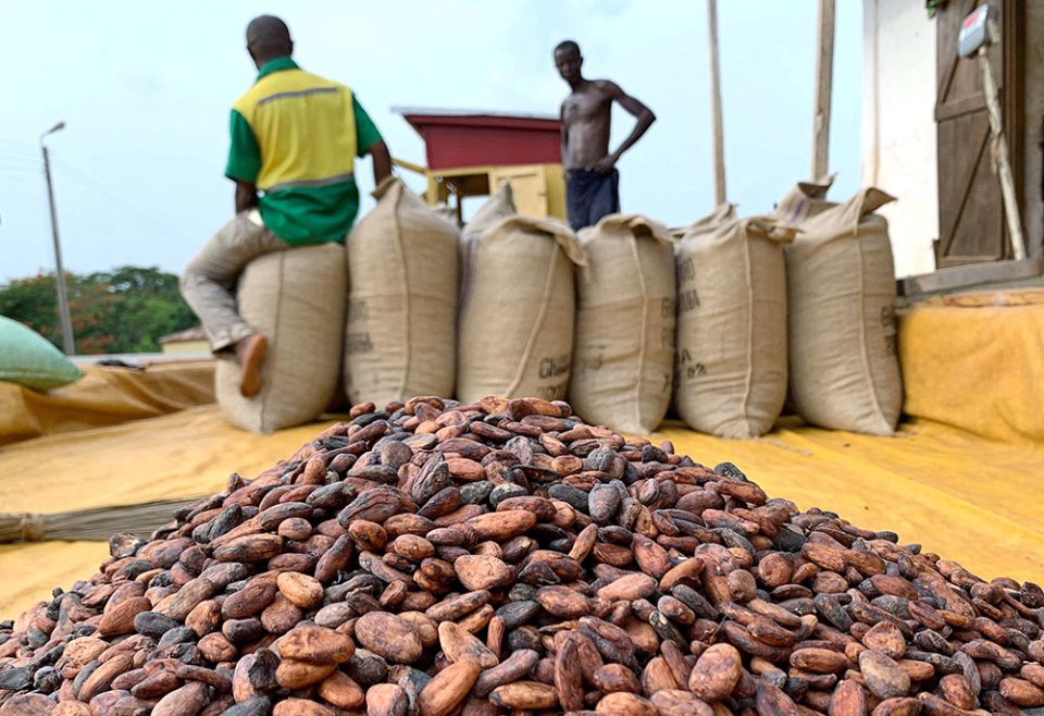 Two workers are pictured near sacks of cocoa beans standing next to a warehouse in 2020 in Atroni, Ghana. (CNS/Reuters/Ange Aboa)