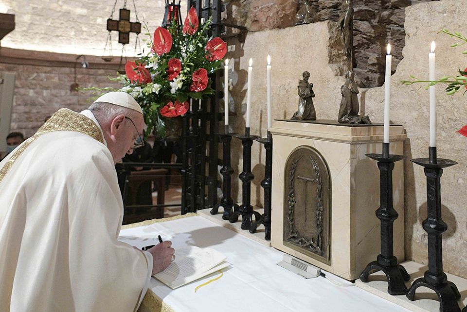 Pope Francis signs his new encyclical, "Fratelli Tutti, on Fraternity and Social Friendship" after celebrating Mass at the Basilica of St. Francis Oct. 3 in Assisi, Italy. (CNS/Vatican Media)