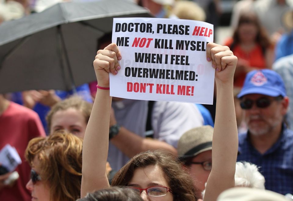 A woman is pictured in a file photo holding up a sign during a rally against assisted suicide on Parliament Hill in Ottawa, Ontario. (CNS/Art Babych)