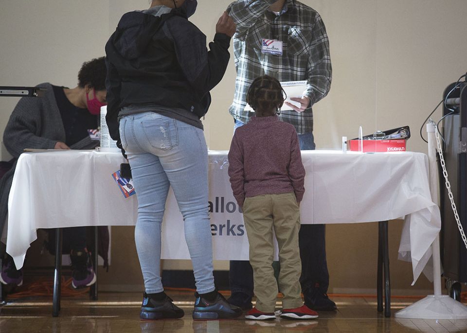 A boy listens to his mom receive instructions on how to vote at Ida B. Wells Middle School in Washington during the presidential election Nov. 3, 2020. (CNS/Tyler Orsburn)