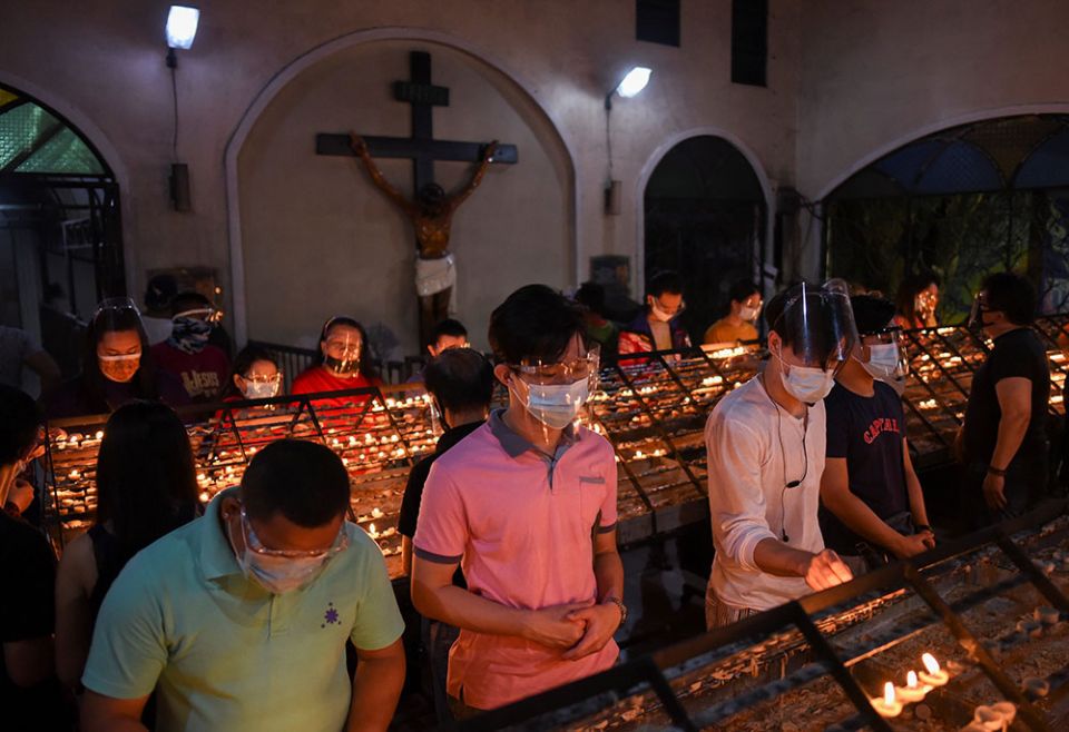 People wearing protective masks and face shields light candles after the first of the nine-day novena Masses for Simbang Gabi at the National Shrine of Our Mother of Perpetual Help in Manila, Philippines, Dec. 16, 2020. (CNS/Reuters/Lisa Marie David)