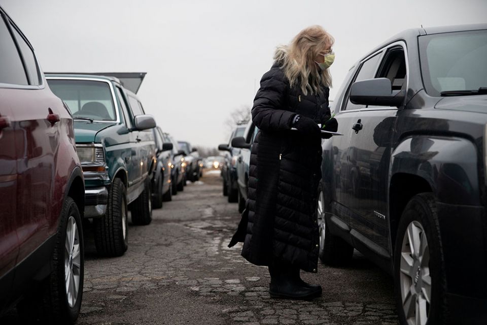 A volunteer from Forgotten Harvest food bank in Warren, Michigan, checks cars before a mobile food pantry distribution Dec. 21, 2020, amid the coronavirus pandemic. (CNS/Reuters/Emily Elconin)