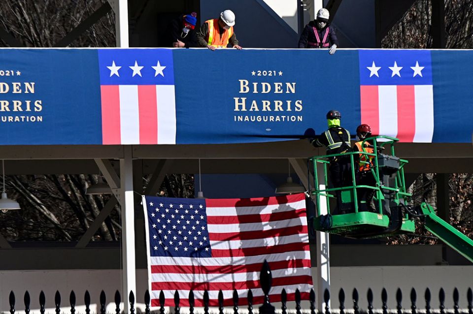 Workers in Washington, D.C., place Biden-Harris inauguration banners on the inaugural parade viewing stand across from the White House Jan. 14, 2021. (CNS/Reuters/Erin Scott)