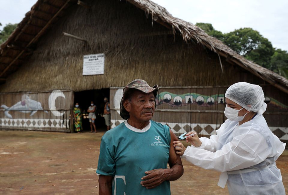 An Indigenous man receives the AstraZeneca/Oxford COVID-19 vaccine from a municipal health worker in the Sustainable Development Reserve of Tupe in Manaus, Brazil, Feb. 9. (CNS/Reuters/Bruno Kelly)