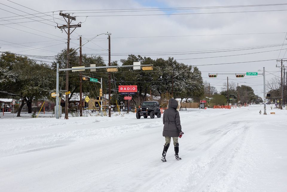 : Stranded without power, a resident walks along a snow-covered road Feb. 16 in Austin, Texas. A failed attempt to provide "rotating blackouts" during Texas' historic winter storm left at least nearly 200,000 people without power in single-digits temperat