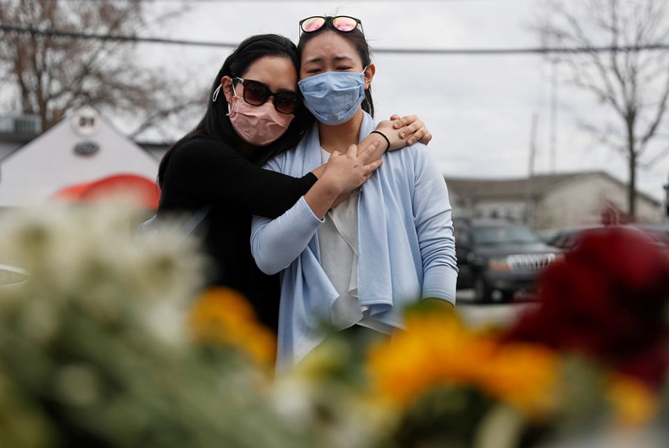 Women in Atlanta embrace March 19, after laying flowers at a makeshift memorial outside the Gold Spa following the deadly shootings March 16 at three day spas in metro Atlanta. Commentator Clarissa V. Aljentera received texts from friends and family, rela