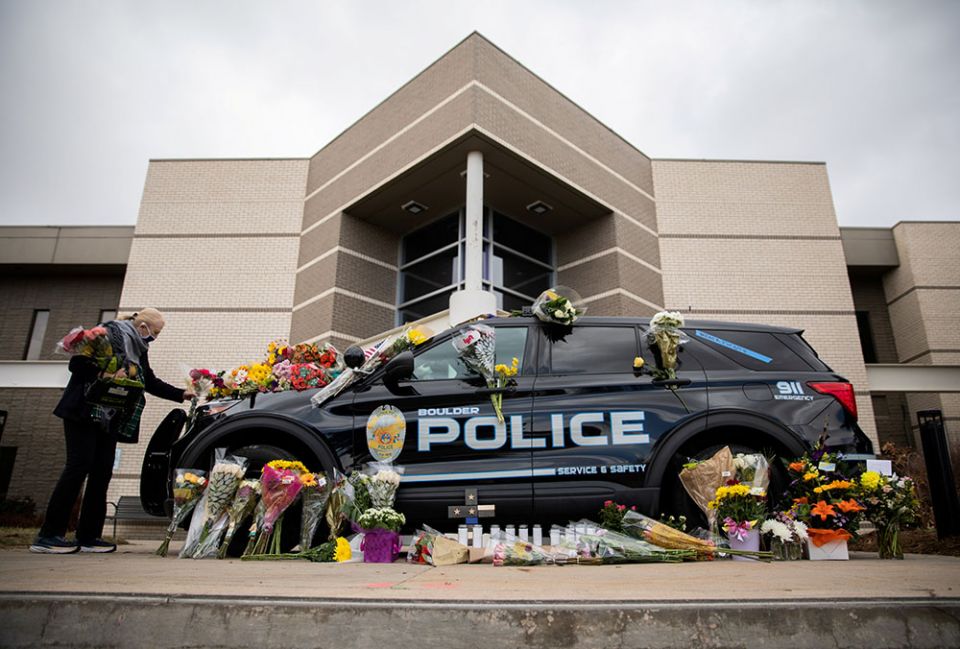Veronica Hebert of Boulder, Colorado, places flowers on the car of Officer Eric Talley March 23. (CNS/Reuters/Alyson McClaran)
