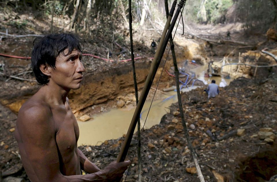 A Yanomami man in 2019 stands near an illegal gold mine on Indigenous land in the heart of Brazil's Amazon rainforest. (CNS/Reuters/Bruno Kelly)