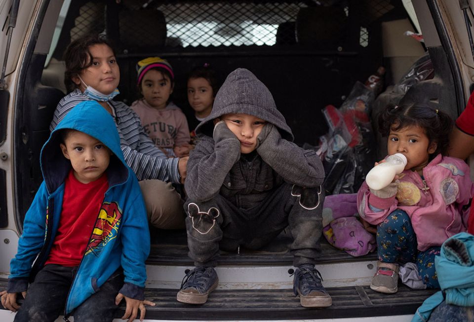 Migrant children from Central America take refuge from the rain in the back of a U.S. Border Patrol vehicle in Penitas, Texas, March 14, as they await to be transported after crossing the Rio Grande into the United States. (CNS/Reuters/Adrees Latif) Migrant children from Central America take refuge from the rain in the back of a U.S. Border Patrol vehicle in Penitas, Texas, March 14, as they await to be transported after crossing the Rio Grande into the United States. (CNS/Reuters/Adrees Latif)