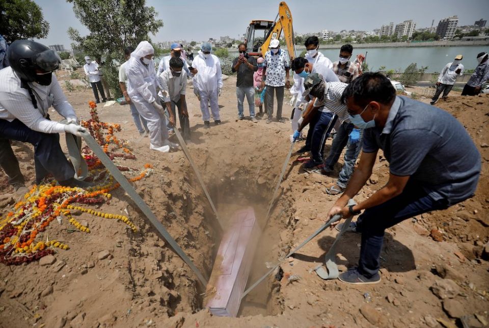 People lower the body of a man who died of COVID-19 into a grave at a cemetery May 3 in Ahmedabad, India. (CNS/Amit Dave, Reuters)