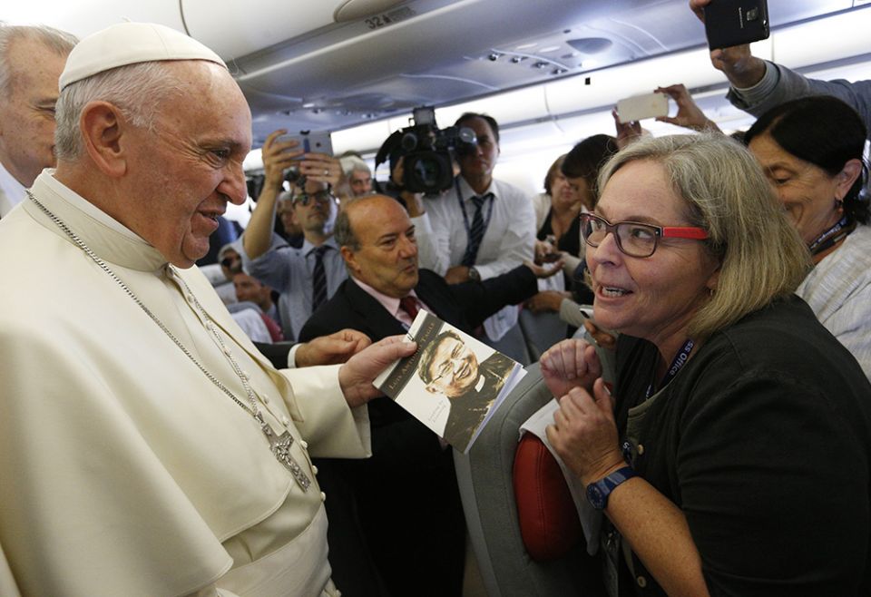 Pope Francis accepts a copy of "Luis Antonio Tagle: Leading by Listening" from Catholic News Service Rome bureau chief Cindy Wooden as he meets journalists aboard his flight from Rome to Havana Sept. 19, 2015. (CNS/Paul Haring)