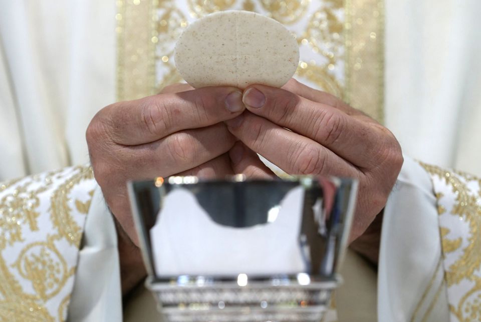 A priest holds the Eucharist in this illustration. (CNS/Bob Roller) A priest holds the Eucharist in this illustration. (CNS/Bob Roller)