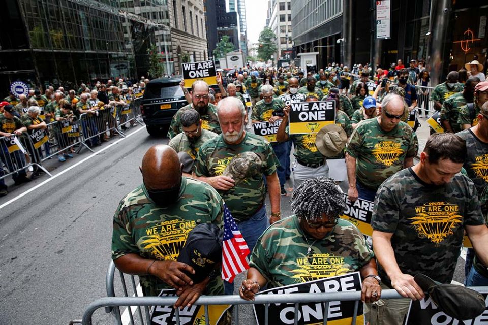 Members of United Mine Workers of America and other labor leaders bow in prayer while picketing July 28, 2021, outside BlackRock's headquarters in New York City as part of the union's strike at Warrior Met Coal Mine. (CNS/Reuters/Brendan McDermid)