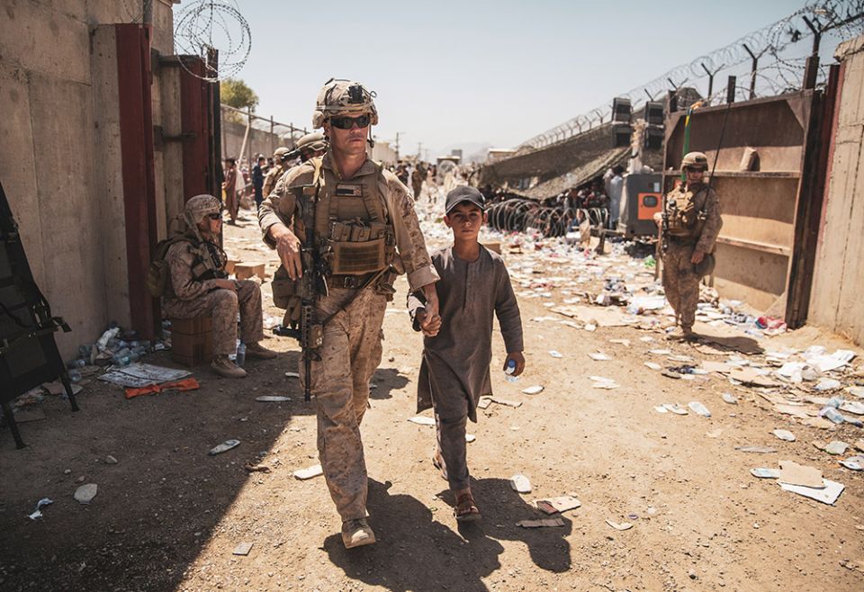 A U.S. Marine escorts a child to his family during an evacuation at Hamid Karzai International Airport Aug. 24, 2021, in Kabul, Afghanistan. (CNS/Handout via Reuters/U.S. Marine Corps/Sgt. Samuel Ruiz)