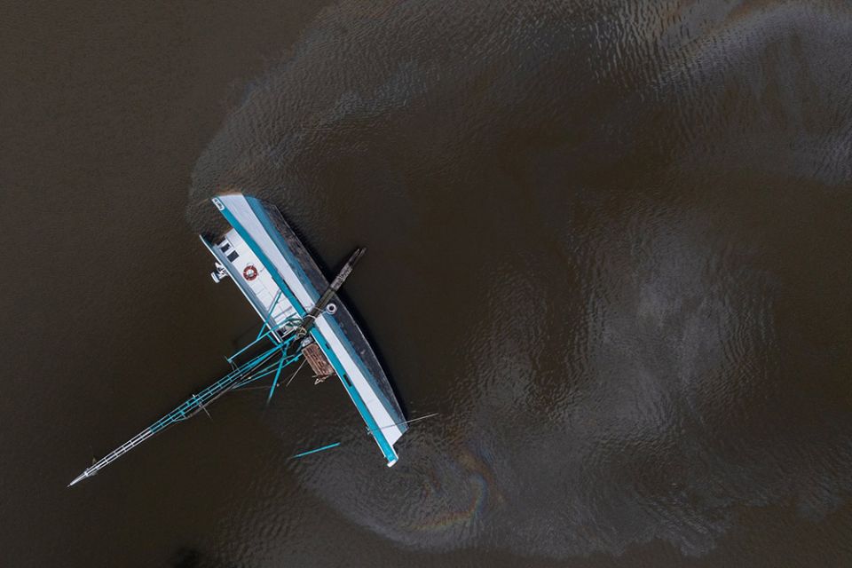 Fuel leaks from a capsized boat along Bayou Lafourche in Galliano, Louisiana, Aug. 31, in the aftermath of Hurricane Ida. (CNS/Reuters/Adrees Latif)
