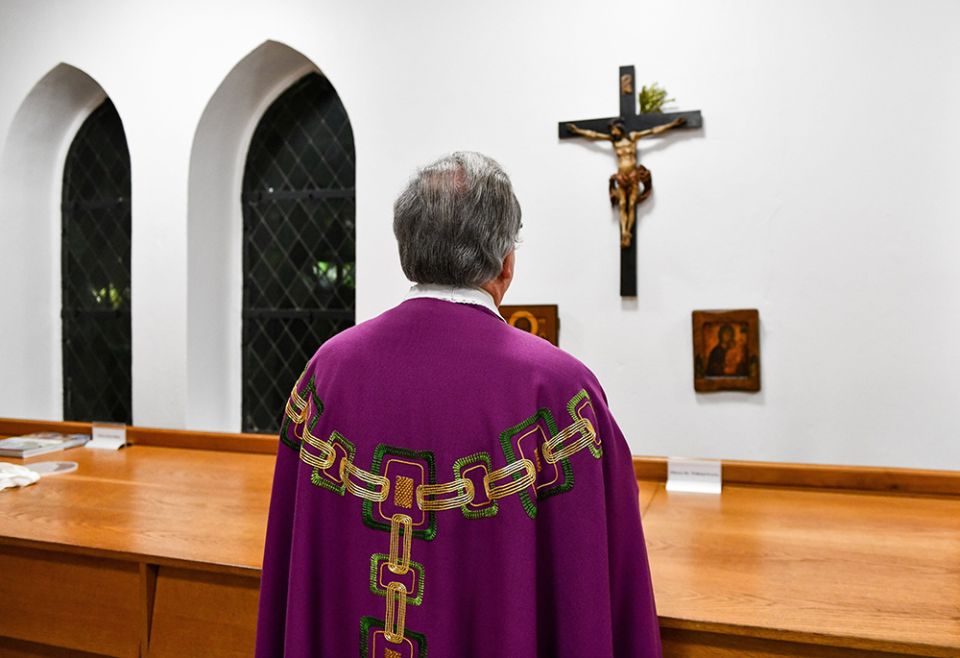 A priest prays in front of the crucifix in the sacristy before Mass in Bonn, Germany, Jan. 24, 2018. (CNS/KNA/Harald Oppitz)