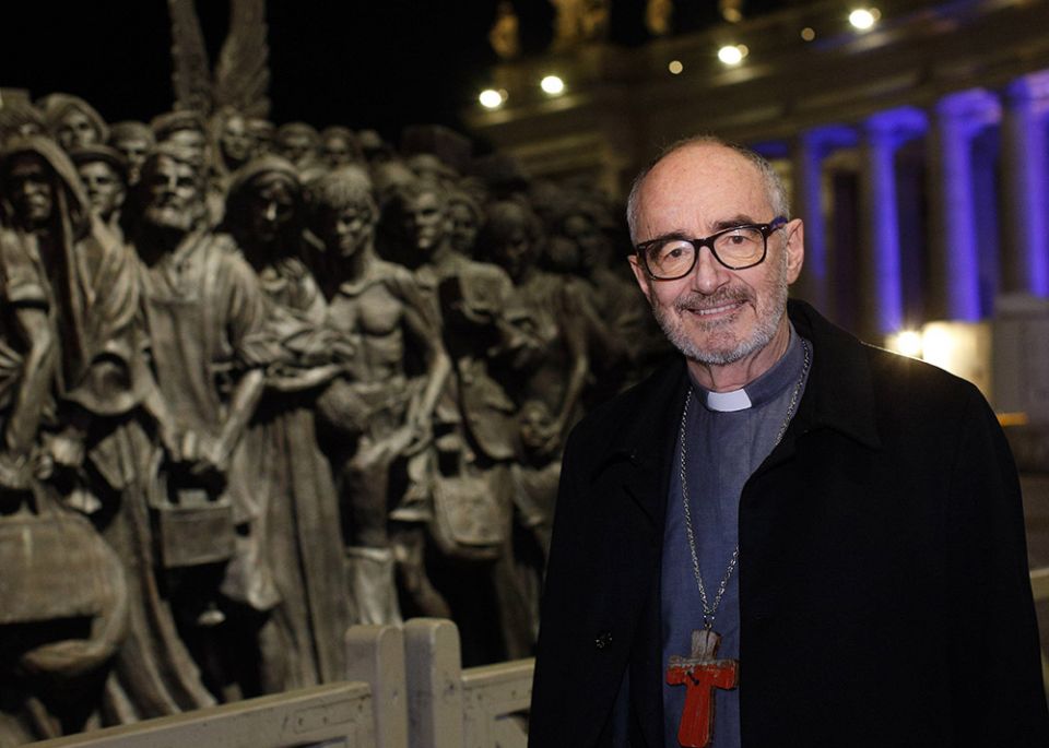 Canadian Cardinal Michael Czerny, undersecretary for migrants and refugees at the Vatican Dicastery for Promoting Integral Human Development, poses for a photo at the "Angels Unawares" statue in St. Peter's Square at the Vatican Dec. 15, 2020. (CNS)