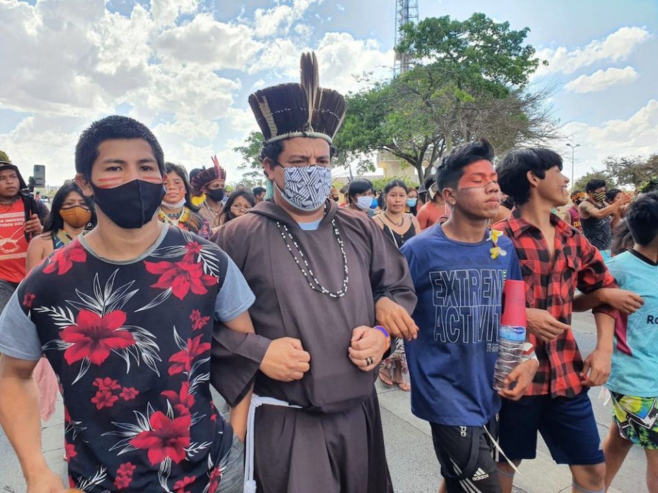 Capuchin Franciscan Fr. Mateus Bento dos Santos, in headdress, joins others during a march for Indigenous rights in early September in Brasilia, Brazil. (CNS photo/Marina Oliveira, courtesy CIMI)