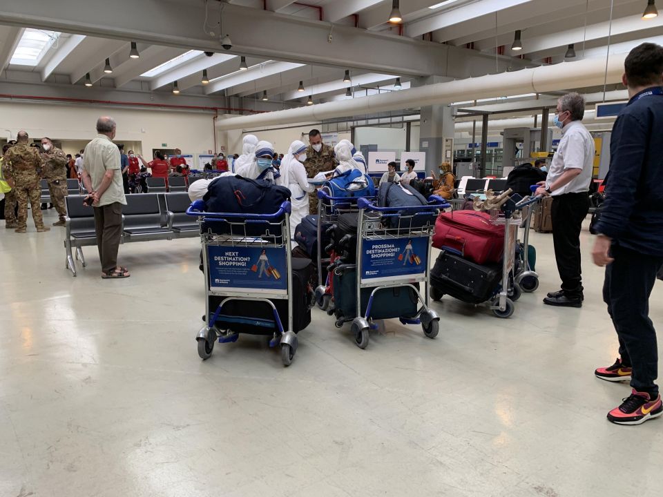 Barnabite Father Giovanni Scalese holds a baggage trolley, right, as he arrives with five Missionaries of Charity nuns at Rome's Fiumicino airport Aug. 25, 2021, after the group was evacuated from Afghanistan. Father Scalese, who was head of the sole Cath