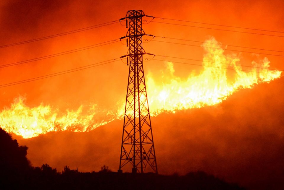 A wind-driven wildfire burns near a power line tower Oct. 10, 2019, in Sylmar, California. (CNS/Reuters/Gene Blevins)