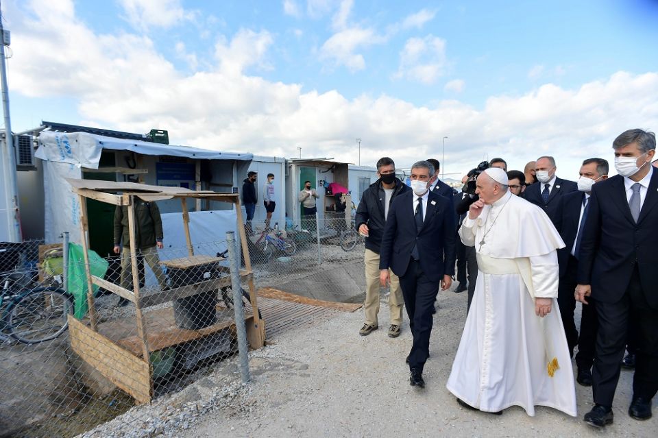 Refugees stand outside their shelters as Pope Francis visits the government-run Reception and Identification Center in Mytilene, Greece, Dec. 5, 2021