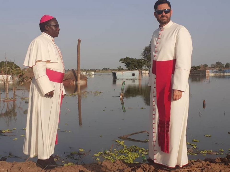 Bishop Stephen Nyodho Ador Majwok of Malakal, South Sudan, and Msgr. Ionut Paul Strejac, chargé d'affaires at the Vatican Embassy in South Sudan, stand in Bentiu, where ongoing flooding has submerged buildings, homes and markets. (CNS photo/courtesy Bisho
