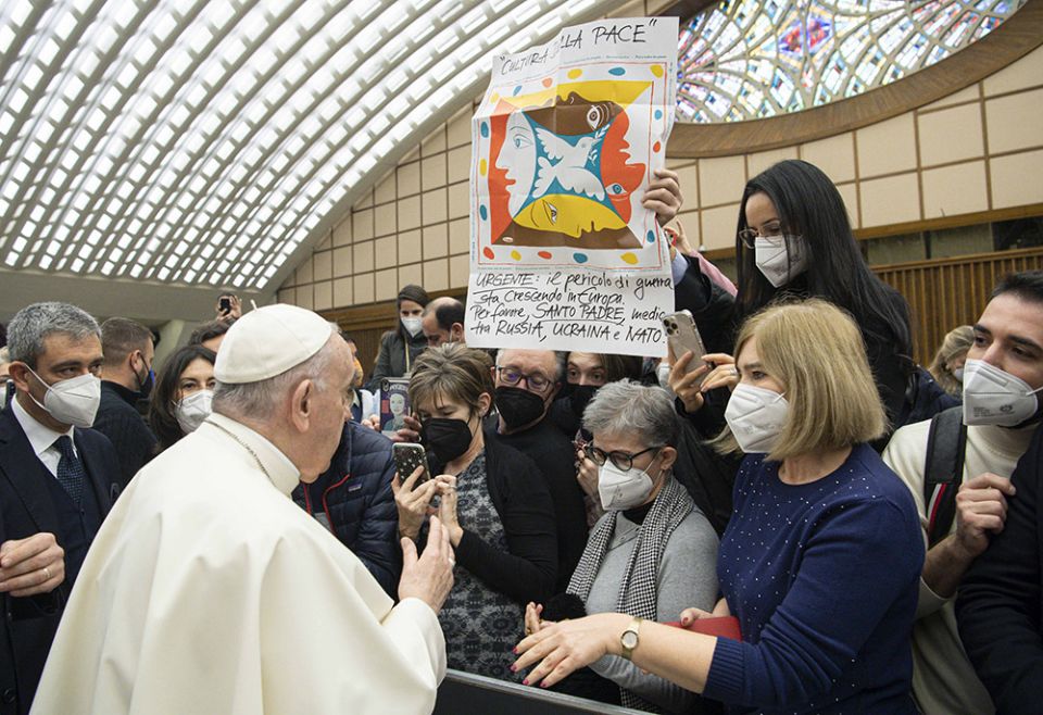 Pope Francis greets people near a banner in Italian calling for the pope's intervention between Russia, Ukraine and NATO, during his general audience in the Paul VI hall Jan 19 at the Vatican. (CNS/Vatican Media)