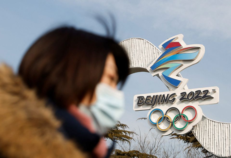 A woman wearing a protective mask walks past the Beijing 2022 Winter Olympic logo Jan. 18. The Olympic & Paralympic Winter Games in Beijing will be held Feb. 4-20 and March 4-13. (CNS/Reuters/Carlos Garcia Rawlins)