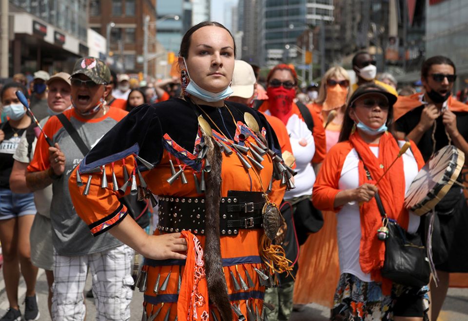 Indigenous performer Danielle Migwans attends a march on Canada Day in Toronto July 1, 2021, after the discovery of hundreds of unmarked graves on the grounds of two former residential schools for Indigenous children in Canada. (CNS/Reuters/Carlos Osorio) Indigenous performer Danielle Migwans attends a march on Canada Day in Toronto July 1, 2021, after the discovery of hundreds of unmarked graves on the grounds of two former residential schools for Indigenous children in Canada. (CNS/Reuters/Carlos Osorio)
