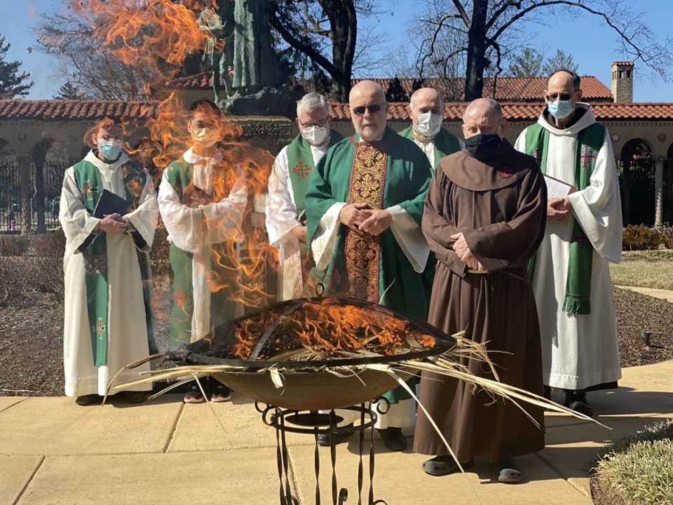A group of friars from the Franciscan Monastery of the Holy Land in Washington look on Feb. 27, 2022, as a fire burns out after turning last year's Palm Sunday palms into ashes. (CNS photo/Rhina Guidos)