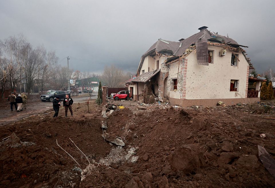 People in Hatne, Ukraine, stand next to a crater in front of a house damaged by recent shelling March 3, as Russia's invasion of Ukraine continues. (CNS/Reuters/Serhii Nuzhnenko) People in Hatne, Ukraine, stand next to a crater in front of a house damaged by recent shelling March 3, as Russia's invasion of Ukraine continues. (CNS/Reuters/Serhii Nuzhnenko)