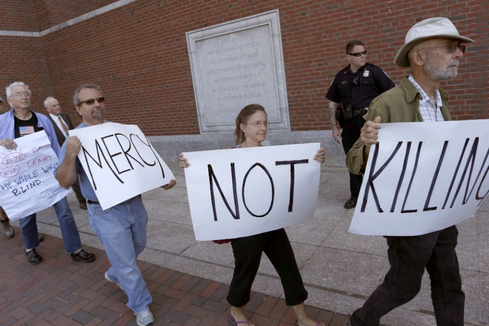 Death penalty protesters at the federal courthouse in Boston walk with signs before the formal sentencing of convicted Boston Marathon bomber Dzhokhar Tsarnaev June 24, 2015. (CNS/Reuters/Dominick Reuter)