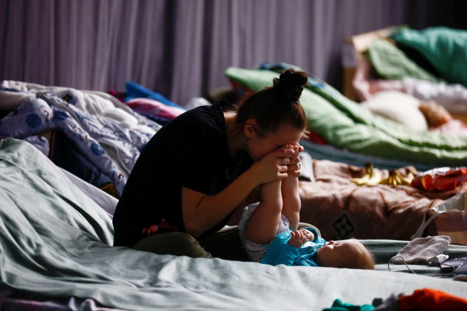   A woman plays with her child in a sports hall of a high school transformed into temporary accommodation for people fleeing the Russian war of Ukraine in Przemysl, Poland, March 9, 2022. (CNS photo/Yara Nardi, Reuters)
