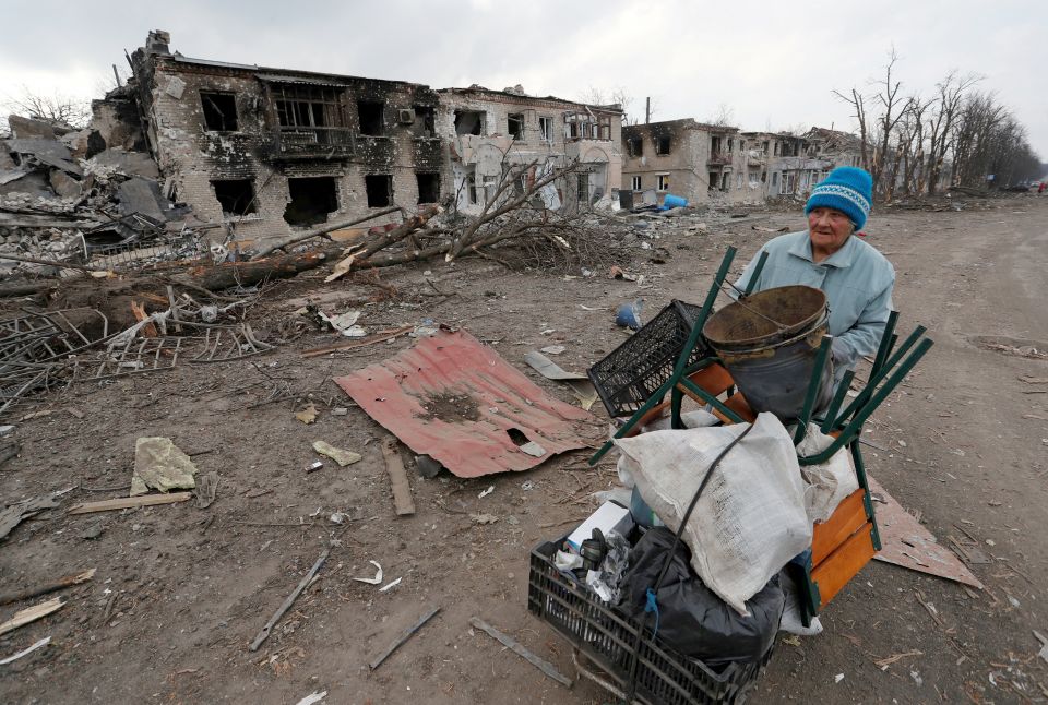 A woman pushes a cart with her belongings past buildings damaged during the Russian war in the separatist-controlled town of Volnovakha, Ukraine, March 15, 2022. (CNS photo/Alexander Ermochenko, Reuters)