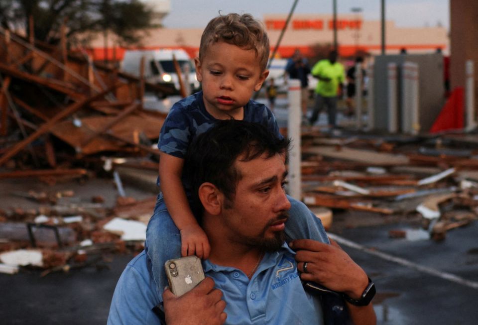 Arturo Ortega and his son, Kaysen Ortega, 2, survey the damage to a shopping center after a tornado touched down in Round Rock, Texas, March 21, 2022. (CNS/Reuters/Tamir Kalifa)