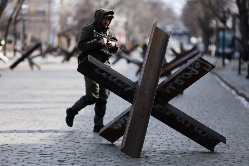 A Ukrainian service member walks past an anti-tank barricade reading "Glory to heroes and death to enemies," in downtown Odesa, Ukraine, March 20, 2022. (CNS photo/Nacho Doce, Reuters)