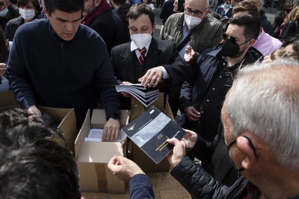 A book commemorating Pope Francis' March 27, 2020, prayer service at the beginning of the COVID-19 pandemic is distributed to people in St. Peter's Square after the pope's Sunday Angelus at the Vatican March 27, 2022. (CNS photo/Vatican Media)