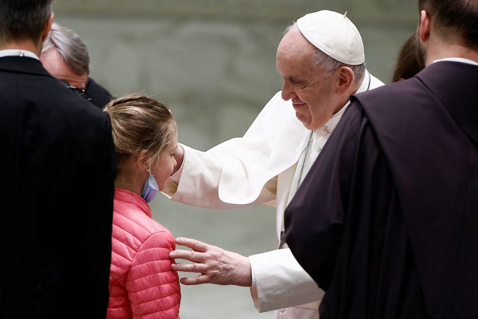Pope Francis blesses a refugee girl who fled Russia's invasion of Ukraine, during the weekly general audience in the Paul VI hall at the Vatican March 30, 2022. (CNS photo/Guglielmo Mangiapane, Reuters)