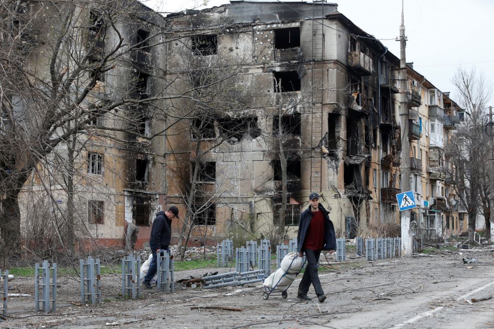 People walk past destroyed apartments in the southern port city of Mariupol, Ukraine, April 18, 2022, during the Russian war. (CNS photo/Alexander Ermochenko, Reuters)