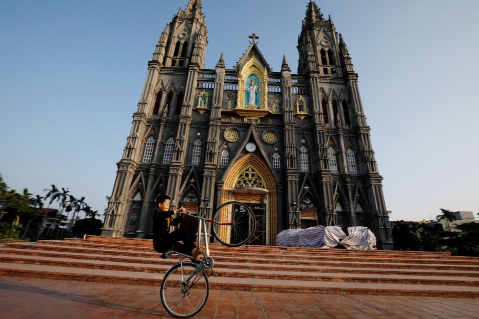 A boy in Nam Dinh, Vietnam, cycles in front of a church Dec. 6, 2020. (CNS photo/Kham, Reuters)